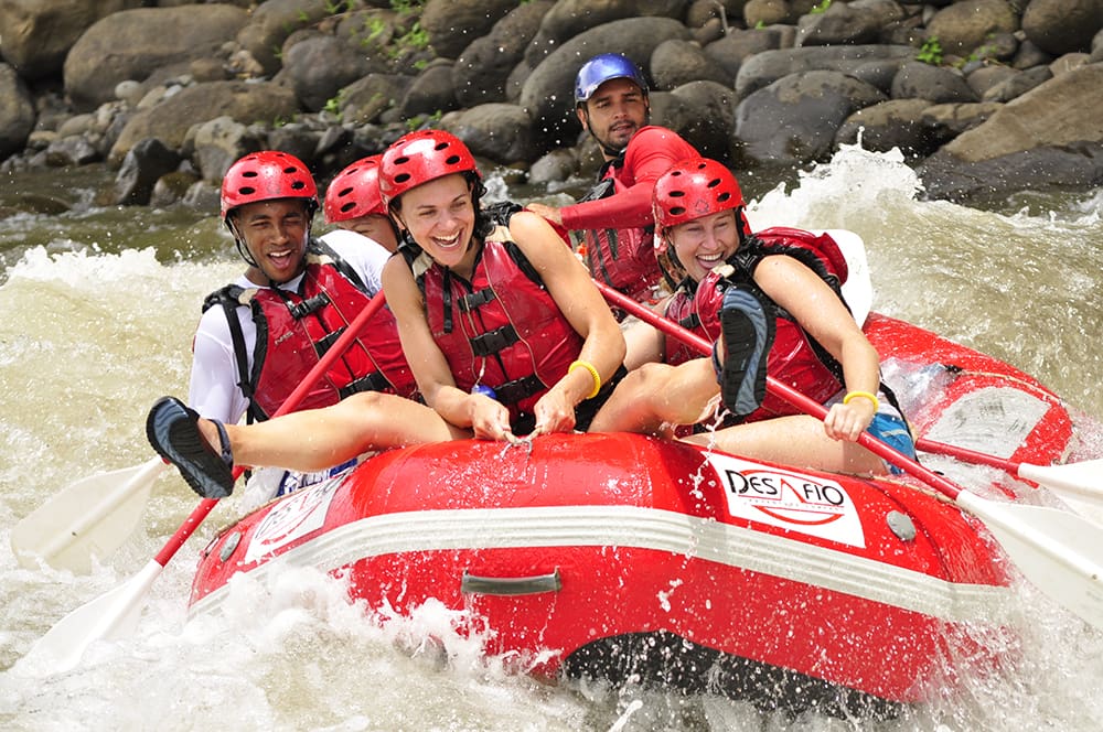 People whitewater rafting and smiling.