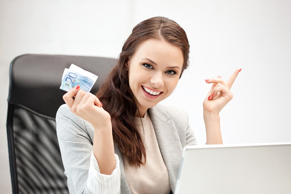 Woman sitting in front of the laptop and holding money.