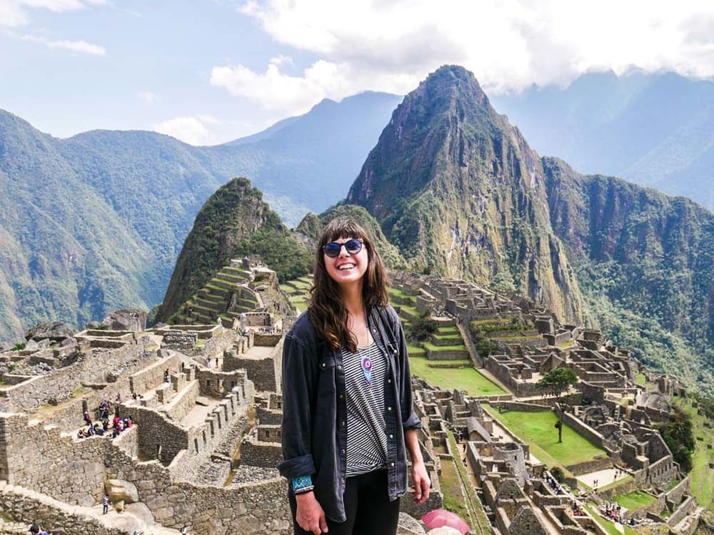 Smiling woman standing in front of Machu Picchu.