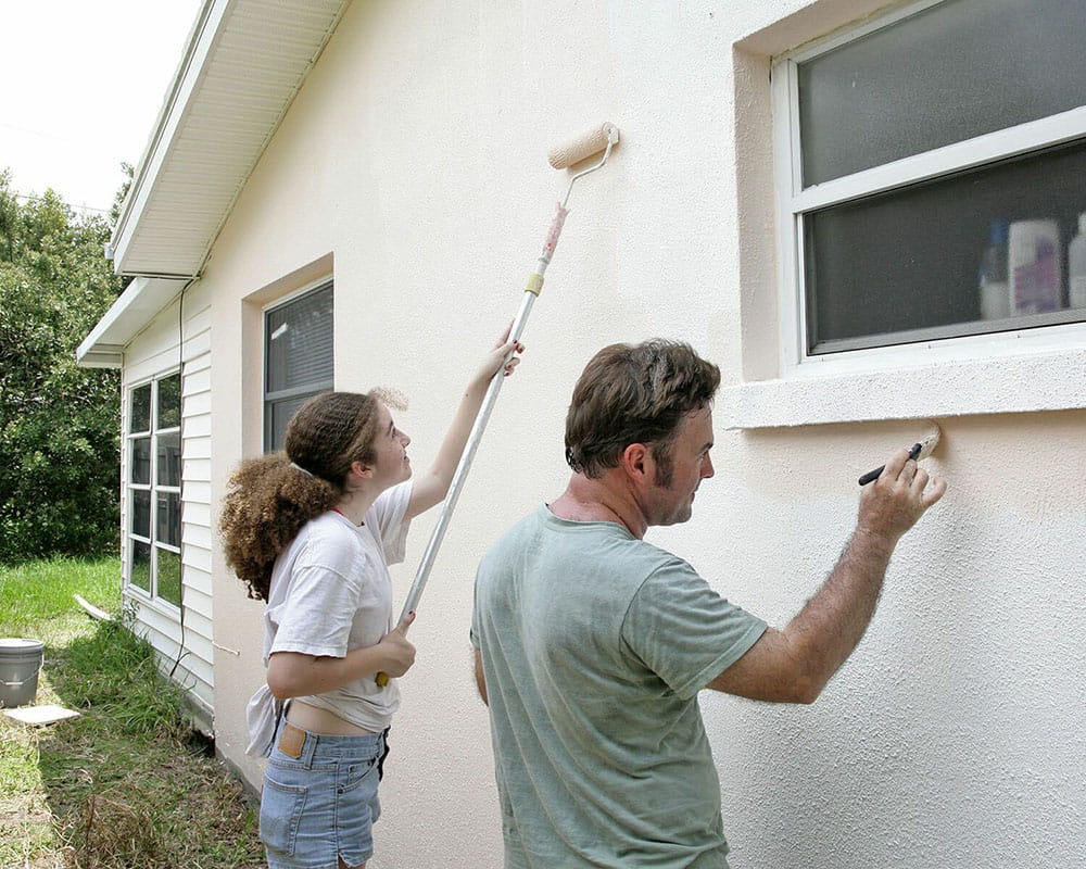 A man and a woman painting a house.