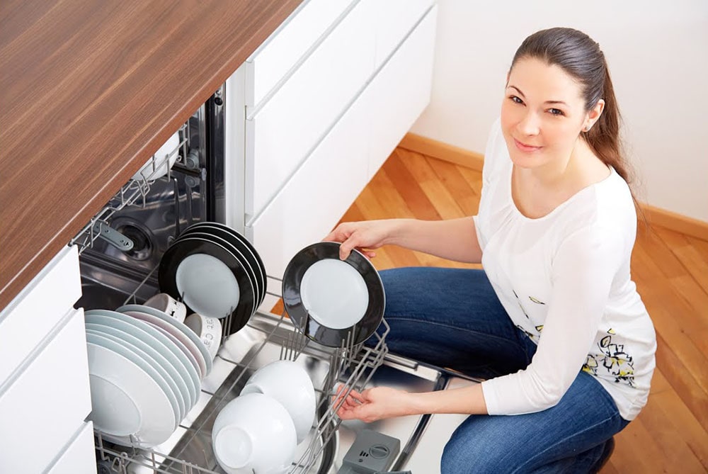 Woman using dishwasher.