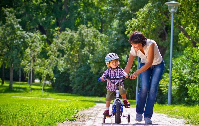 Mother helping her son to ride a bike