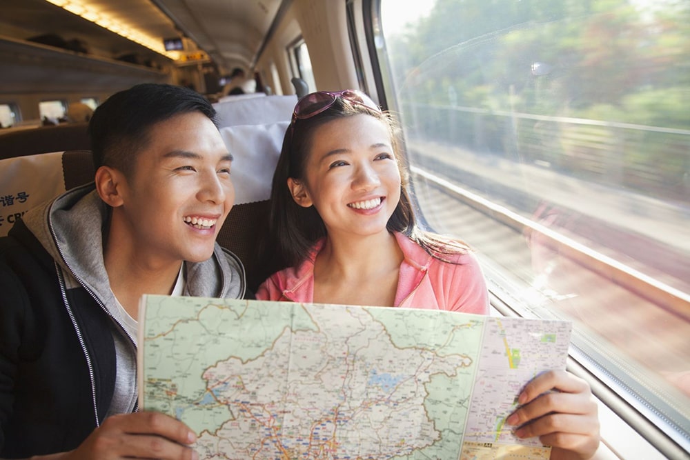 A couple in the train smiling and holding a map.