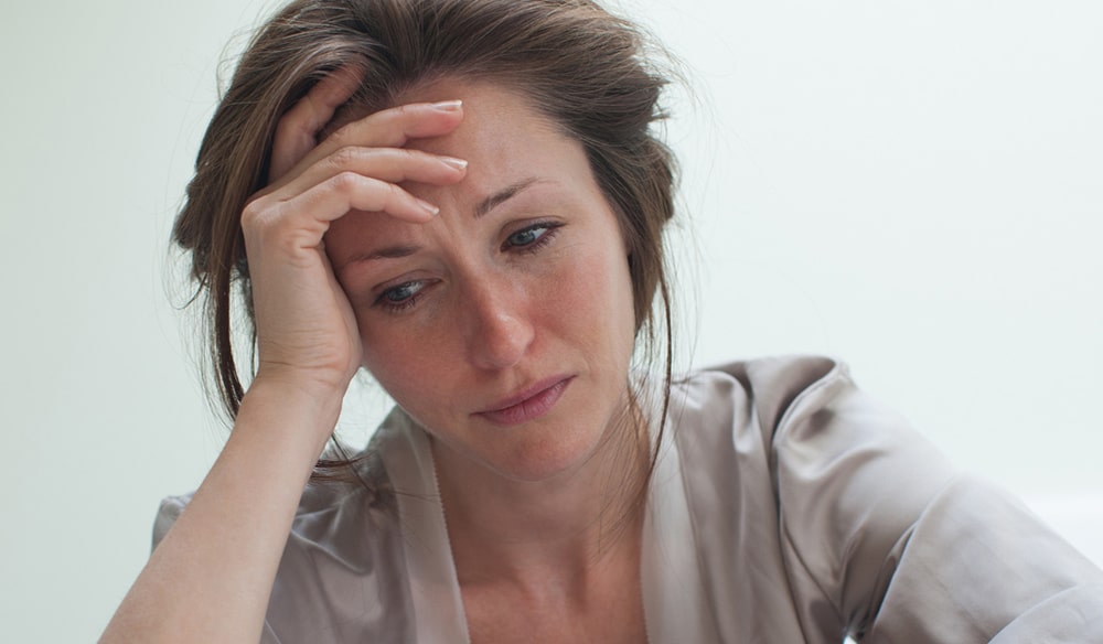 Sad woman holding hand on forehead.