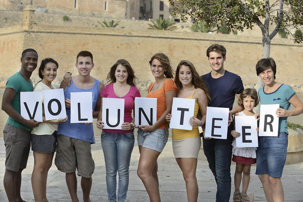 People holding letters forming the word volunteer.