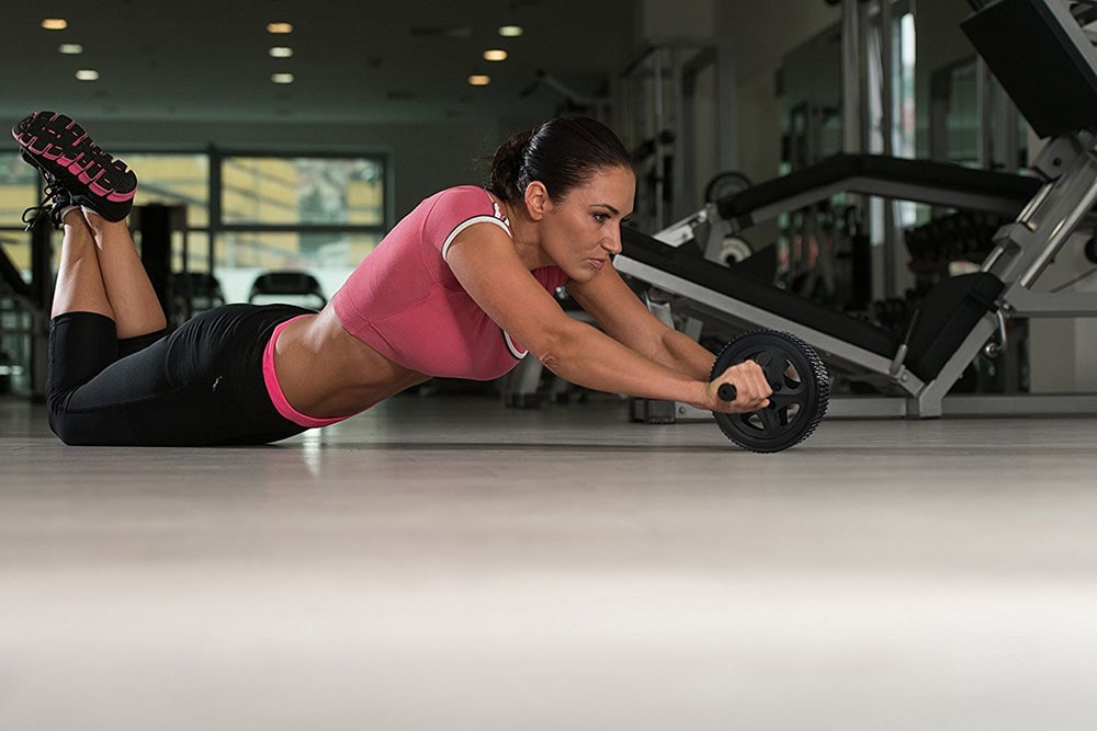 Woman working out with roller wheel.