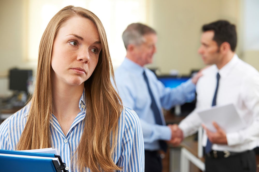 Men shaking hands behind a businesswoman. 