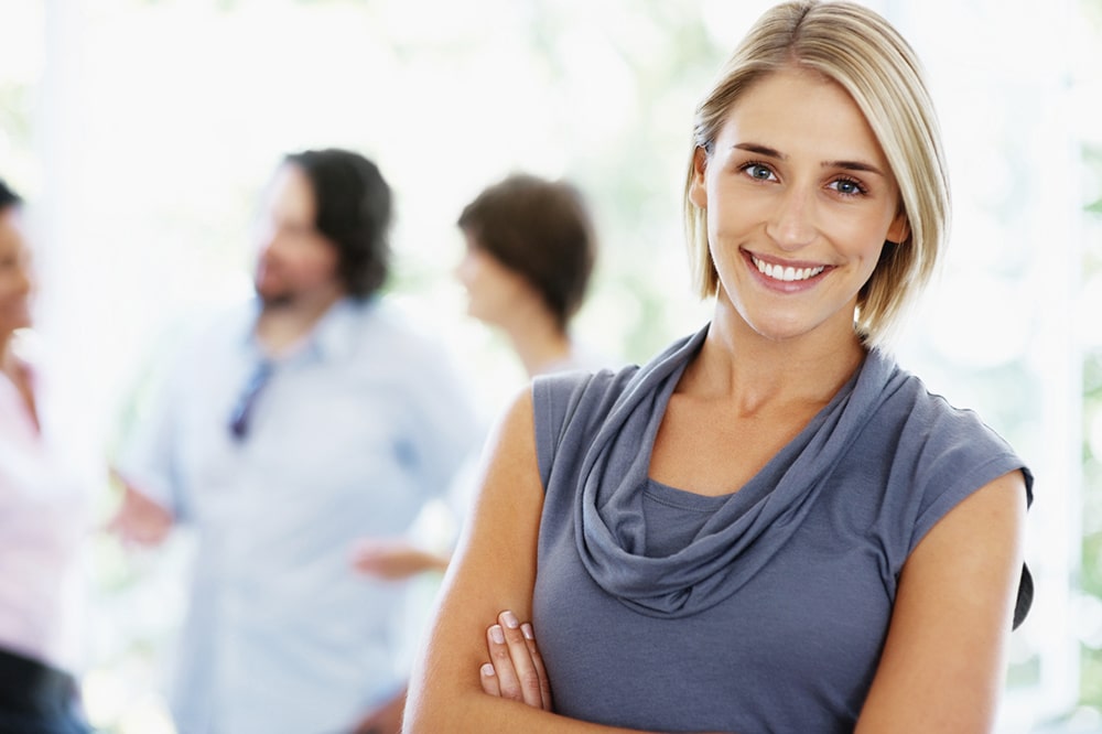 Smiling woman holding her hands crossed.