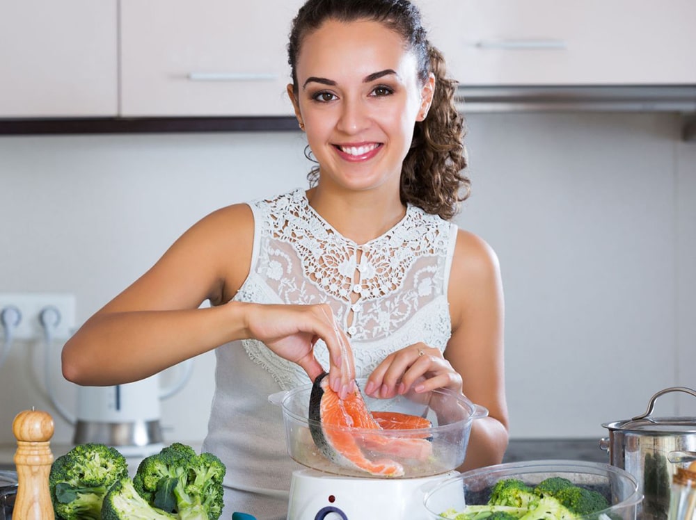 Woman cooking salmon in a steam cooker. 