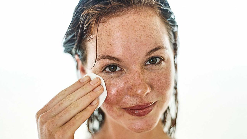 Woman using face cotton pad.