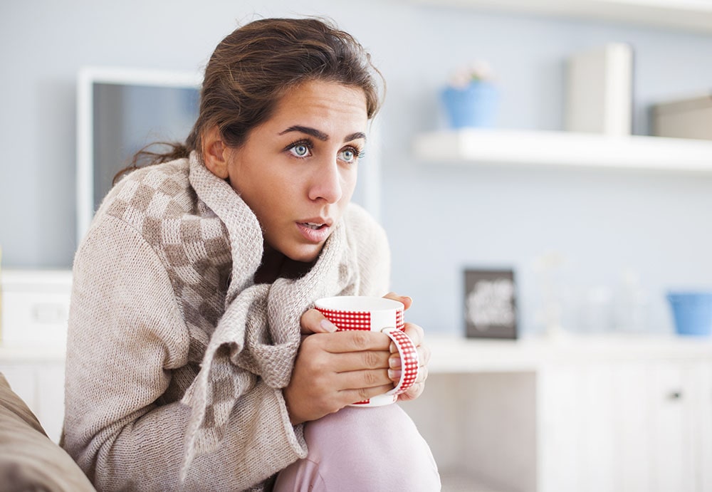 Woman with a cup feeling cold.