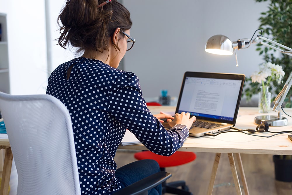 Woman sitting at the desk and working on the laptop.