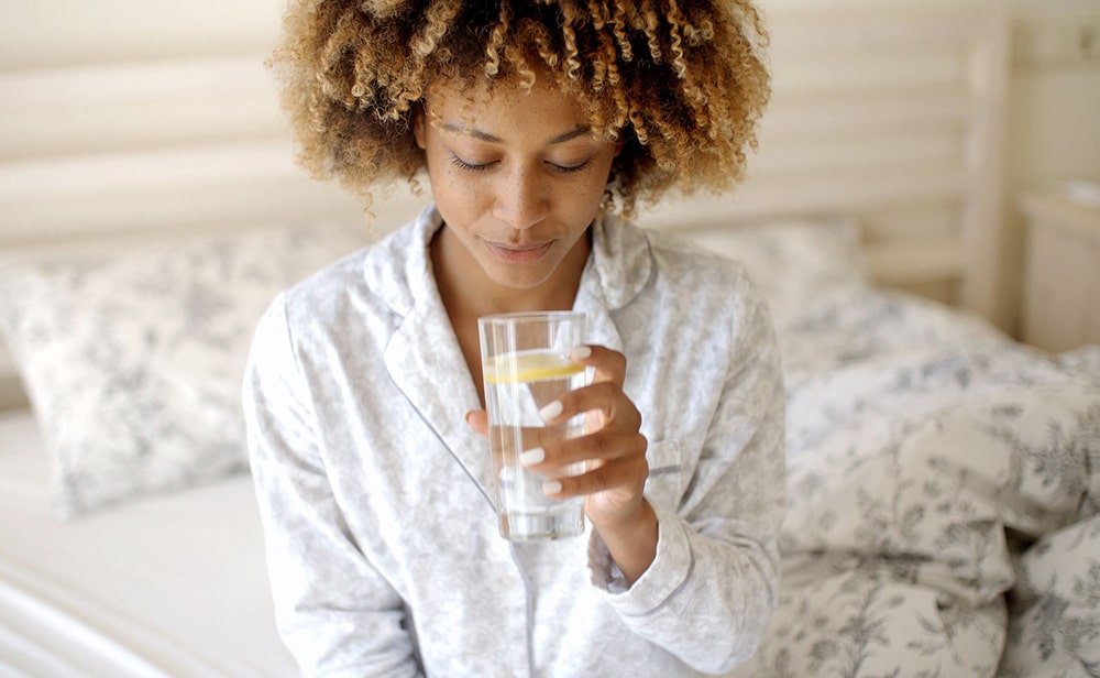 Woman drinking a glass of water with lemon.