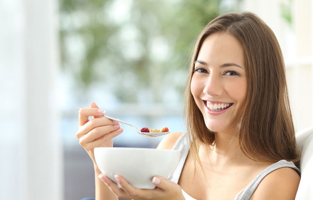 Woman eating oatmeal with fruits.