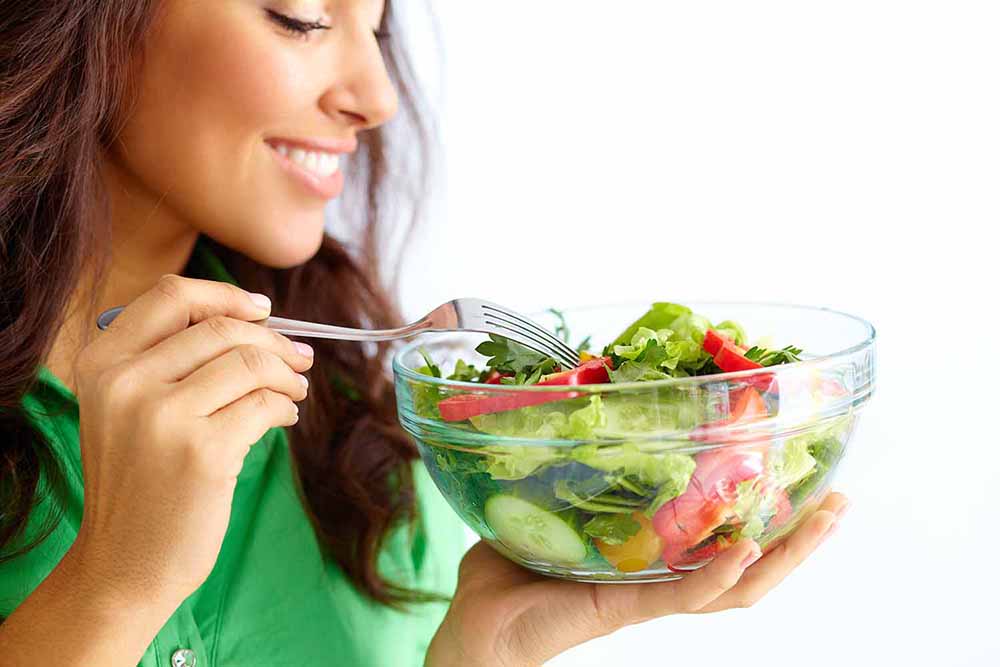 Woman eating a bowl of salad.