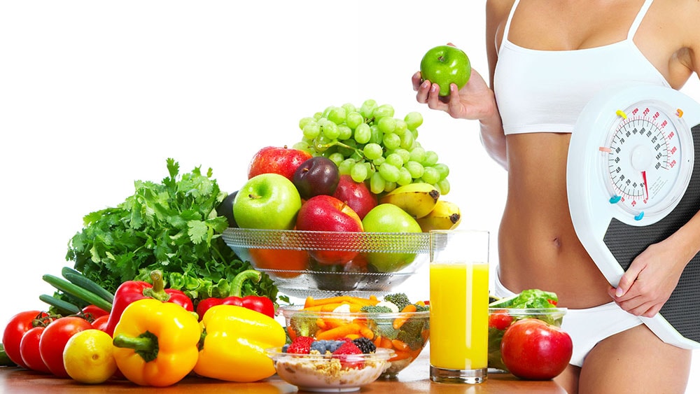 woman holding scales and an apple standing next to fruits