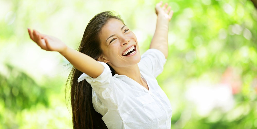 Smiling woman holding hands up.