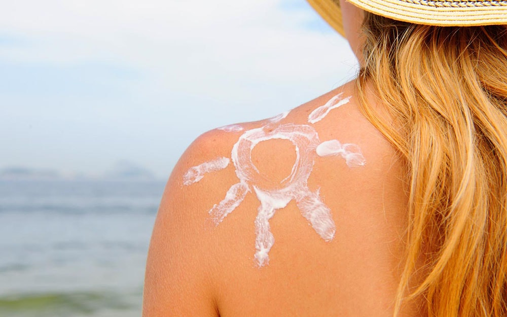 Sun shaped cream on the woman's shoulder.