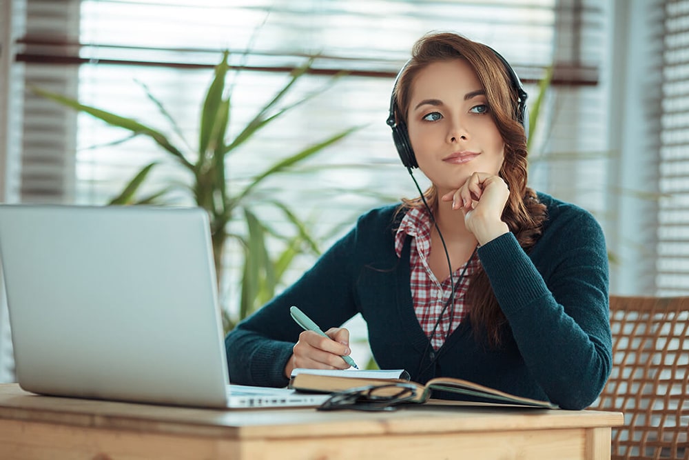 Woman wearing headphones sitting at her desk.