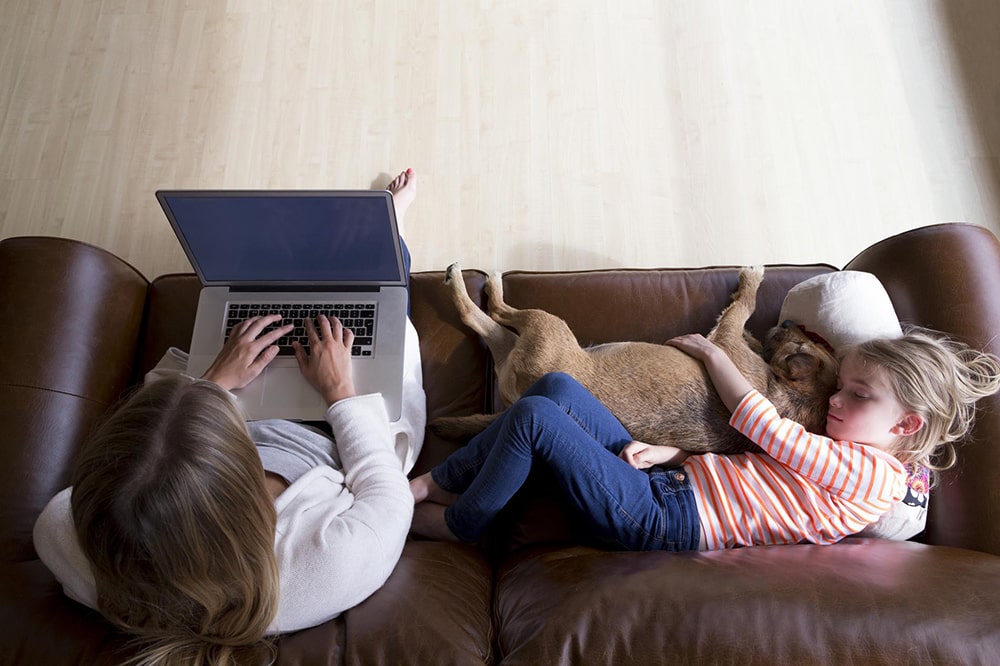 Woman sitting on a sofa with a girl and a dog.