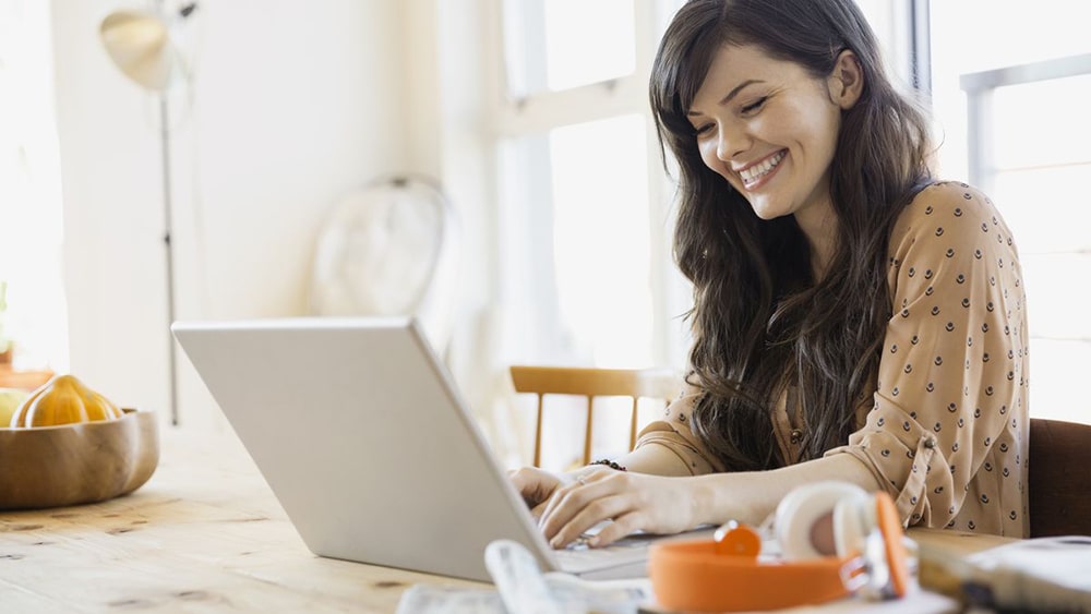 Smiling woman working on laptop.